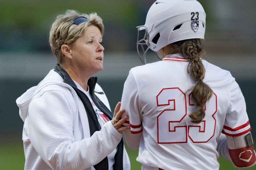 (Matthew Hinton | AP) Utah head coach Amy Hogue talks to infielder Aliya Belarde (23) during an NCAA softball game on Saturday, Feb. 18, 2023, in Baton Rouge, La.