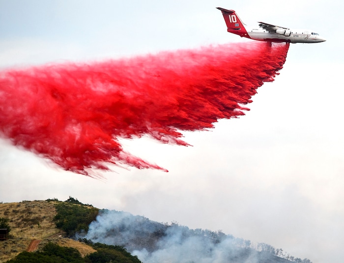 (Steve Griffin  |  The Salt Lake Tribune)  A jet drops fire retardant on a burning ridge line above homes in Bountiful Tuesday August 29, 2017.