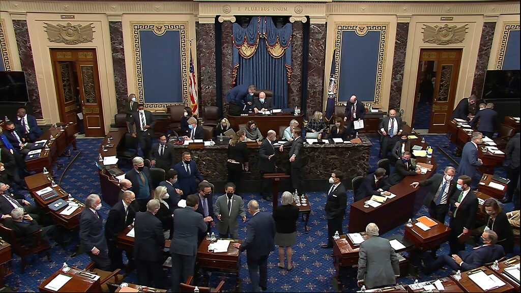 In this image from video, senators gather around Senate Majority Leader Chuck Schumer of N.Y., and House impeachment manager Rep. Jamie Raskin, D-Md., bottom left, after Sen. Mike Lee, R-Utah, made an objection to evidence presented by House impeachment managers during the second impeachment trial of former President Donald Trump in the Senate at the U.S. Capitol in Washington, Wednesday, Feb. 10, 2021. (Senate Television via AP)