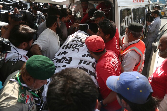 People offload the body of a police officer killed during a shootout at the Chinese Consulate in Karachi, Pakistan, Friday, Nov. 23, 2018. Armed separatists stormed the Chinese Consulate in Pakistan's southern port city of Karachi on Friday, triggering an intense hour-long shootout during which two police officers and all three assailants were killed, Pakistani officials said. (AP Photo/Shakil Adil)