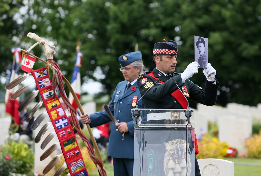 (David Vincent | AP) A member of the Canadian Armed Forces holds a photo of a Canadian World War II soldier during a ceremony at the Beny-sur-Mer Canadian War Cemetery in Reviers, Normandy, France, Wednesday, June 5, 2019. A ceremony was held on Wednesday for Canadians who fell on the beaches and in the bitter bridgehead battles of Normandy during World War II.