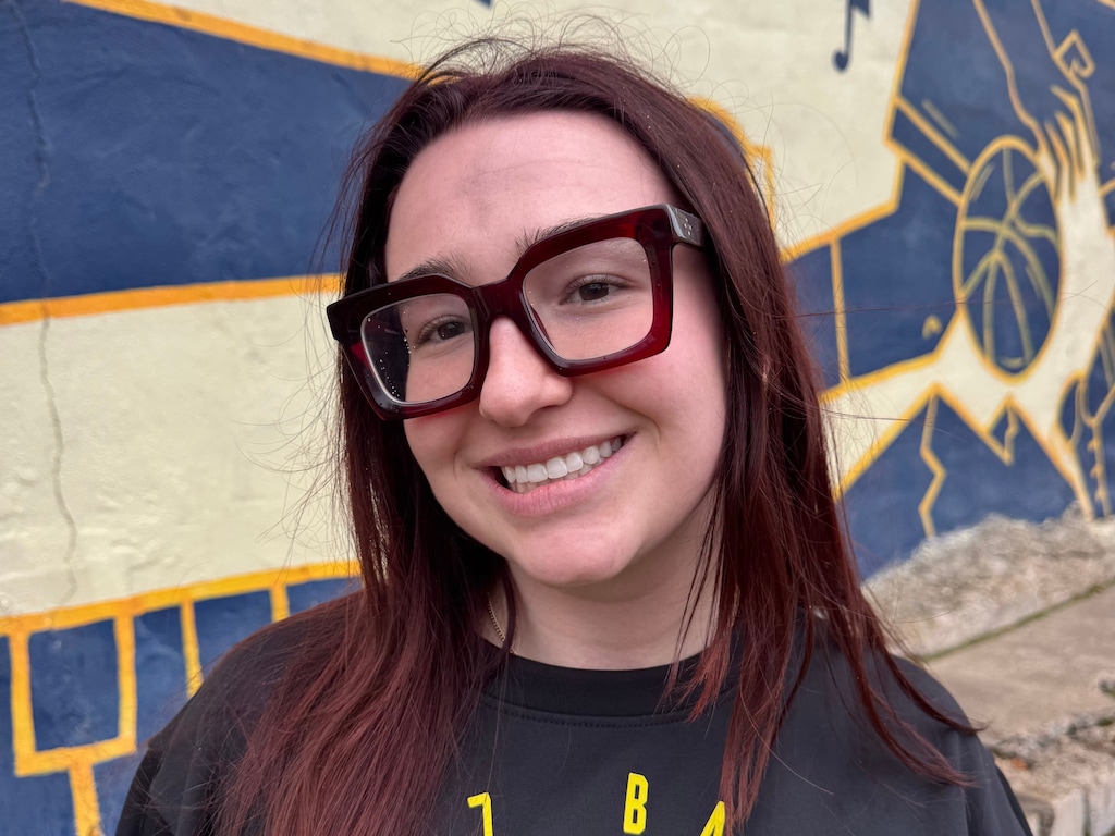 (Ava Hart | Amplify Utah) Madeline Mirrione, a team attendant with the Utah Jazz, stands near Karabo Poppy's Utah Jazz mural in downtown Salt Lake City.