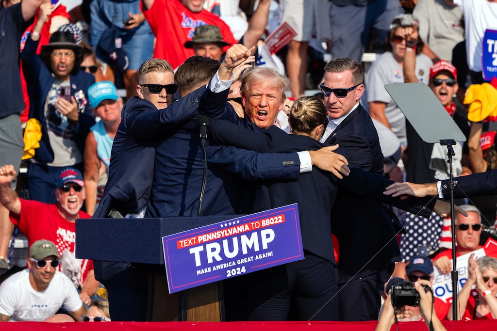 A bloodied Donald Trump is surrounded by Secret Service agents at a campaign rally in Butler, Pa, on Saturday, July, 13, 2024. The former president was escorted off the stage by Secret Service agents and into his motorcade just minutes into his rally in Butler, Pa., on Saturday, after a series of pops that sounded like gunshots rang out. (Eric Lee/The New York Times)