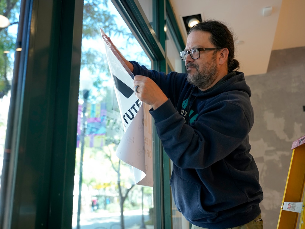 (Bethany Baker  |  The Salt Lake Tribune) Horacio Rodriguez, the chair of the board for the Mestizo Institute of Culture and Arts, hangs up a sign ahead of a gallery opening in the organization’s new space at The Gateway in downtown Salt Lake City on Friday Oct. 6, 2023.
