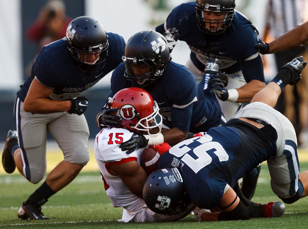 (Trent Nelson | The Salt Lake Tribune) Utah State defenders tackle Utah's John White during the first quarter of a football game in Logan, Friday, Sept. 7, 2012.