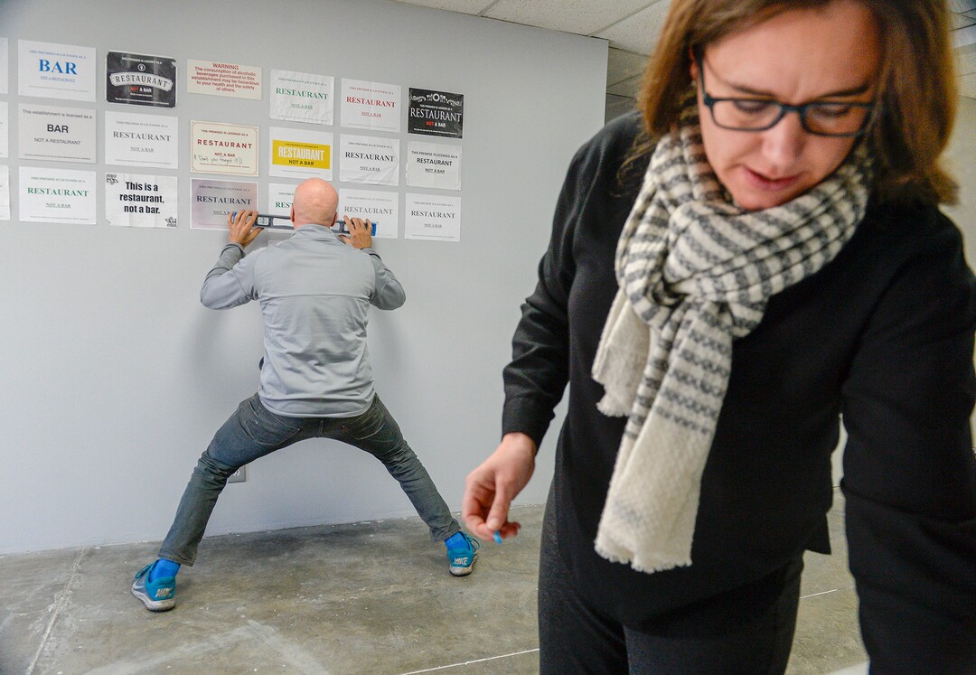 Leah Hogsten  |  The Salt Lake Tribune  Salt Lake City liquor attorney Tanner Lenart and Nox Contemporary art gallery owner John Sproul tack the ill-fated artistic memorials of Utah’s now-defunct liquor law on the walls of Sproul's gallery. The opening reception for the installation is Friday, Nov. 16, and runs thru the end of November. Last May, the state law requiring restaurants and bars to display DABC signs labeling themselves as a “bar” or a “restaurant” was repealed. Once a perceived nuisance by restaurateurs, the signs are celebrated art. The installation "This Is Art, Not a Sign" is a collage made of "This Is a Restaurant, Not a Bar" liquor signs that were once required in Utah restaurants.