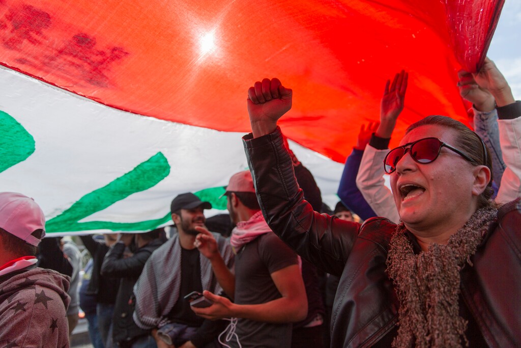 (Nasser Nasser | AP) Anti government protesters chant anti Iran and anti U.S. slogans under a big Iraqi flag that they carry during the ongoing protests in Tahrir square, Baghdad, Iraq, Friday, Jan. 10, 2020.