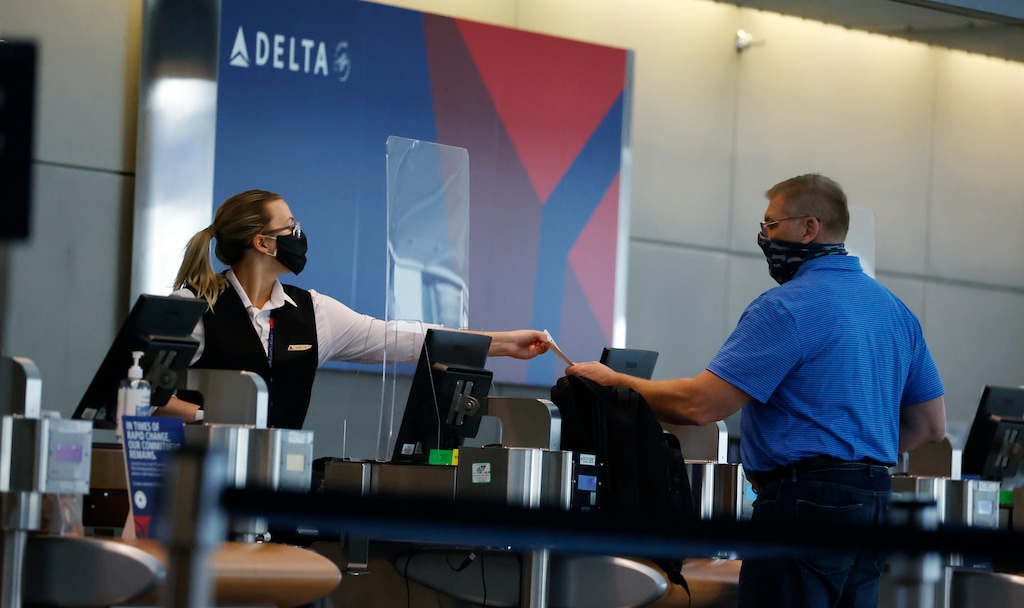 (David Zalubowski | AP file photo) A ticketing agent for Delta Air Lines hands a boarding pass to a passenger as he checks in for a flight in the main terminal of Denver International Airport in Denver on Wednesday, July 22, 2020.