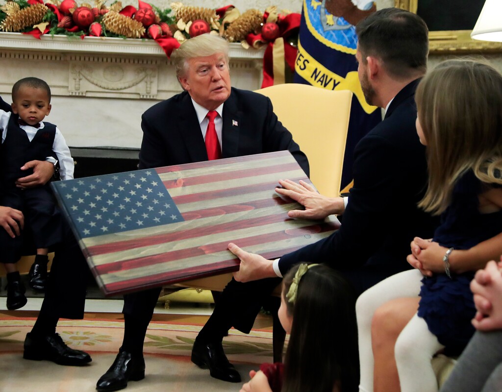 President Donald Trump is presented by Brian Steorts, owner of Flags of Valor, an American flag made of wood, during a meeting with American business owners and their families in the Oval Office at the White House in Washington, Tuesday, Dec. 5, 2017. (AP Photo/Manuel Balce Ceneta)