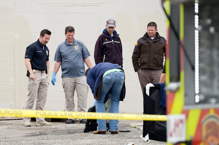 (Leah Hogsten  |  The Salt Lake Tribune)  A West Valley City police detective inspects a backpack found with a body that was recovered from a storm culvert on the grounds of the the vacant Kmart building at 4100 South and 1770 West in West Valley City, Friday, April 6, 2018. 