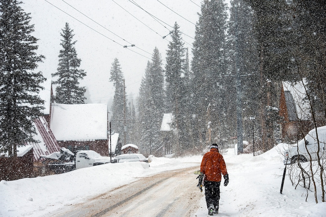 (Chris Detrick  |  The Salt Lake Tribune) A snowboarder walks along South Brighton Loop Road in Brighton Saturday, December 23, 2017.  