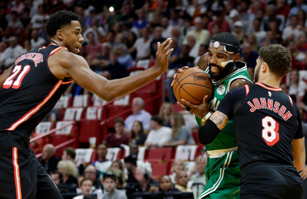 Boston Celtics' Kyrie Irving, center, drives as Miami Heat's Hassan Whiteside (21) and Tyler Johnson (8) defend during the first half of an NBA basketball game, Wednesday, Nov. 22, 2017, in Miami. (AP Photo/Lynne Sladky)