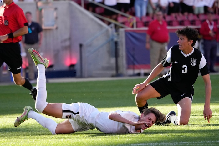 (Francisco Kjolseth | The Salt Lake Tribune) Herriman's Trevor Walk (7) goes down over Davis's Luke Bitner (3) during their 6A State Soccer Championship title game at Rio Tinto Stadium, Wednesday, May 25, 2022. Herriman defeated Davis 1-0 with two seconds left on the clock.