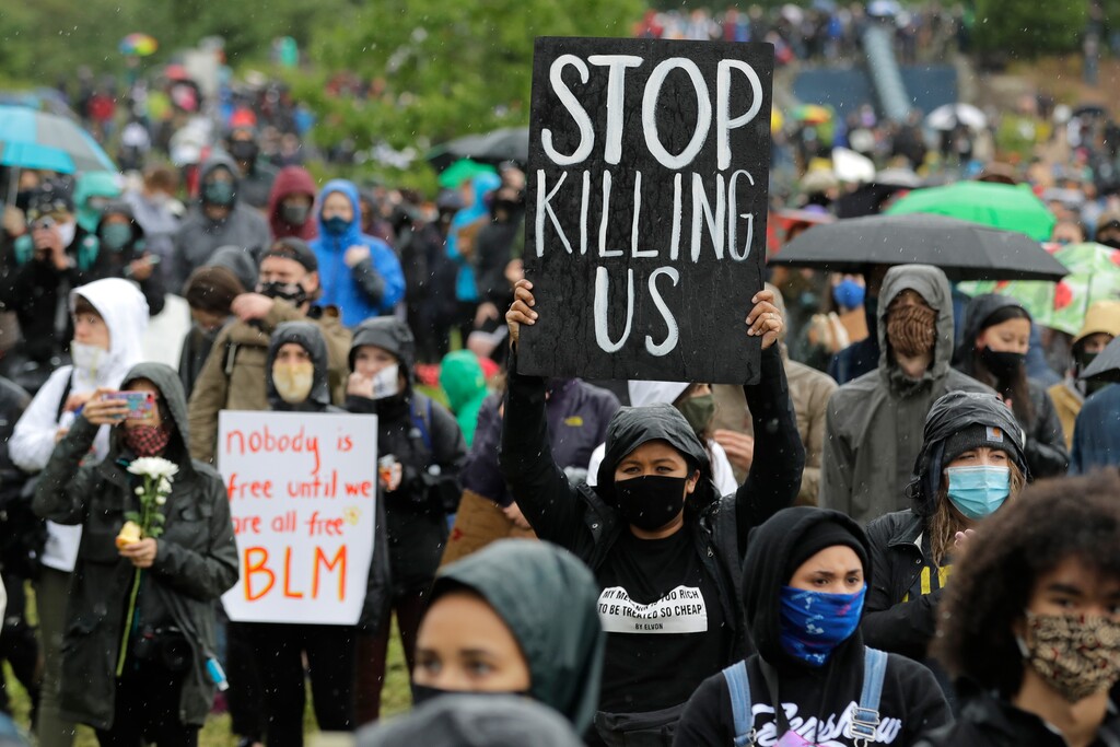 (Ted S. Warren | AP file photo) A protester holds a sign that reads "Stop Killing Us" during a "Silent March" against racial inequality and police brutality that was organized by Black Lives Matter Seattle-King County, Friday, June 12, 2020, in Seattle. People marched for nearly two miles to support Black lives, oppose racism and to call for police reforms among other issues.