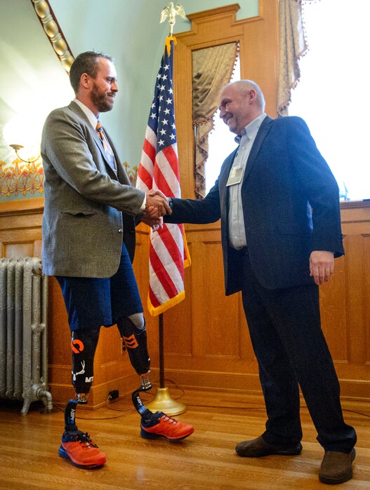 (Steve Griffin  |  The Salt Lake Tribune)   Sidney Smith, left is greeted by Mark Sharrock, of Goldman Sachs, as Smith receives the Golden Key Award at the Governor's Mansion in Salt Lake City onTuesday October 24, 2017. Smith is a double amputee (legs) who is overcoming his disability by competing in triathlons and is a mentor to others with disabilities.