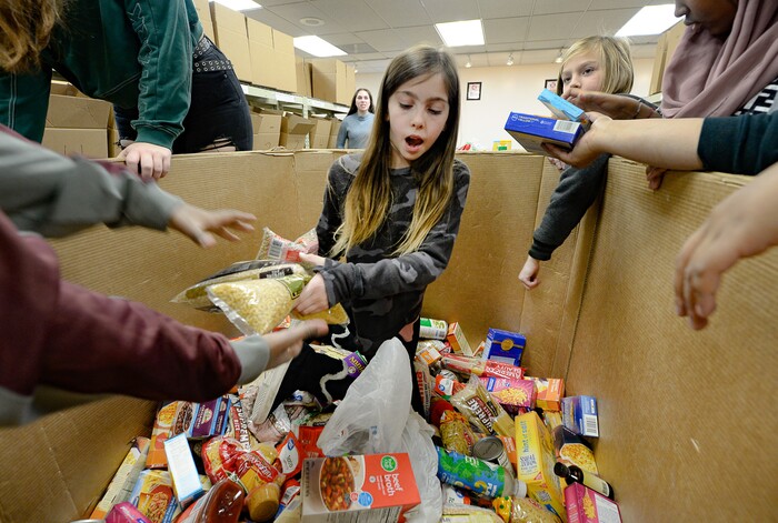 (Francisco Kjolseth  |  The Salt Lake Tribune) Sophia Cannella, 8, helps reach the bottom of the box as she passes food to members of YouthCity Government that involves teens in state-organized, model-government programs, as they volunteer at the Utah Food Bank on Monday, Jan. 20, 2020, to celebrate the 2020 Martin Luther King Jr. Day of Service.
