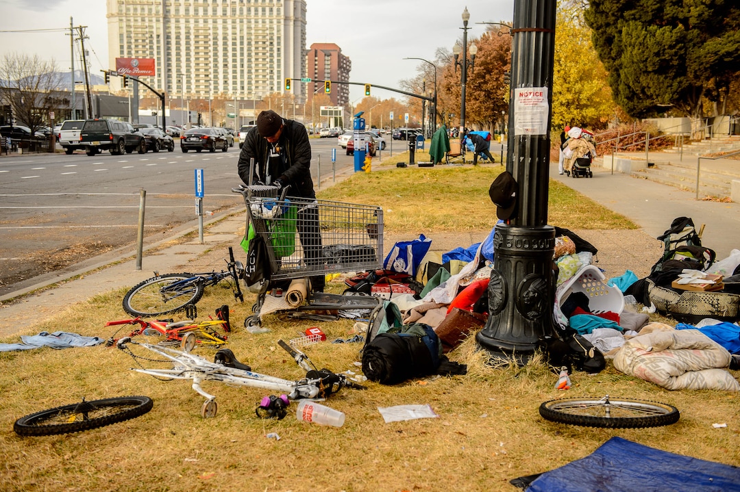 (Trent Nelson | The Salt Lake Tribune) A man empties his belongings from a shopping cart that is being reclaimed near the Salt Lake City Library on Tuesday, Nov. 19, 2019. Antonio Hernandez, an employee of Romac, is assigned to drive around the city and pick up stolen or abandoned shopping carts for return to stores.