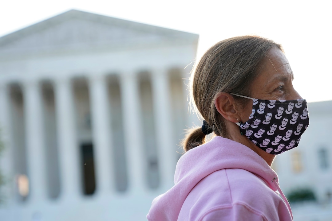 Heather Setzler of Raleigh, N.C., wears a face mask bearing images of Justice Ruth Bader Ginsburg as she stands outside the Supreme Court in Washington, Wednesday, Sept. 23, 2020, before a private ceremony and public viewing for Ginsburg. Ginsburg, 87, died of cancer on Sept. 18. (AP Photo/Patrick Semansky)