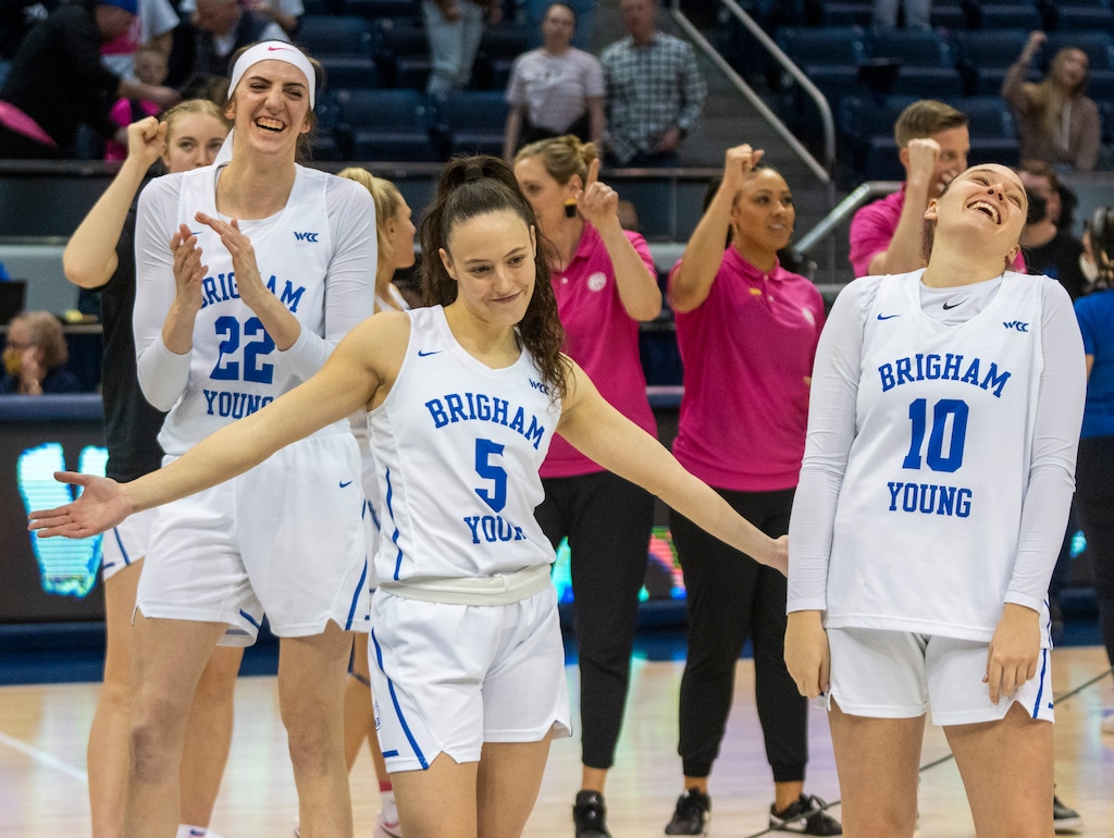 (Rick Egan | The Salt Lake Tribune) BYU Cougars center Sara Hamson (22) and BYU Cougars guard Tegan Graham (10) laugh as Maria Albiero (5) strikes a pose as BYU celebrates their win over the Waves, in women's basketball action between the BYU Cougars and the Pepperdine Waves, at the Marriott Center in Provo, on Thursday, Feb. 10, 2022. Judkins scored his 450th win tonight.