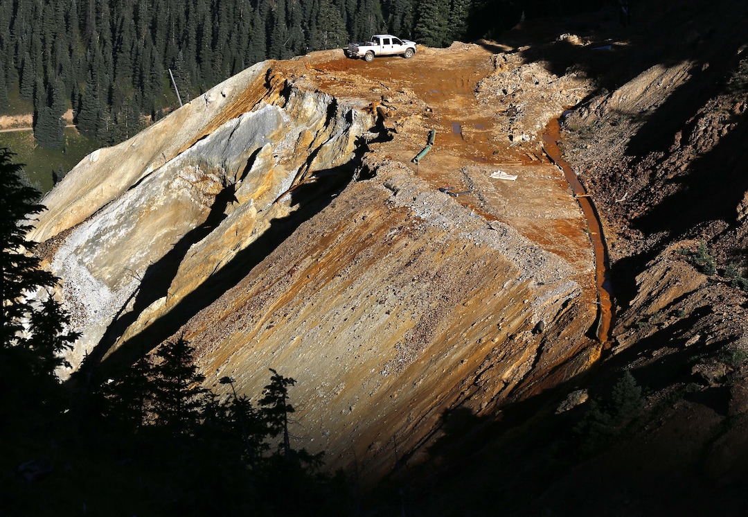 Wastewater flows down a trough, right, from the site of the blowout at the Gold King mine which triggered a major spill of toxic wastewater, outside Silverton, Colo., Thursday, Aug. 13, 2015. It will take years, if not decades, and many millions of dollars to clean up and manage the toxic wastewater from a this Colorado mine that unleashed a 100-mile-long torrent of heavy metals, affecting the livelihoods of residents in three states, according to some experts. (AP Photo/Brennan Linsley)