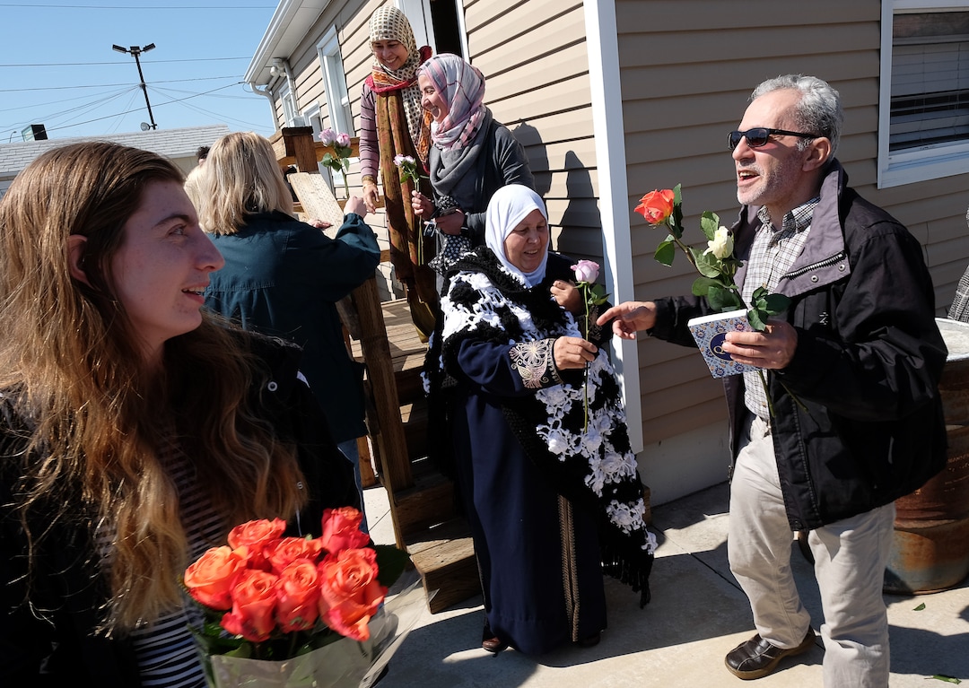 (Francisco Kjolseth  |  The Salt Lake Tribune)  Husam Baker, right, and his mother-in-law Saad Abusaid, center, are presented with flowers by Amelia Damarjian as he and other members of the Al Sahaba Mosque in Orem are shown love and support by the community following Friday prayer services in a show of solidarity after the tragic shootings in New Zealand. 