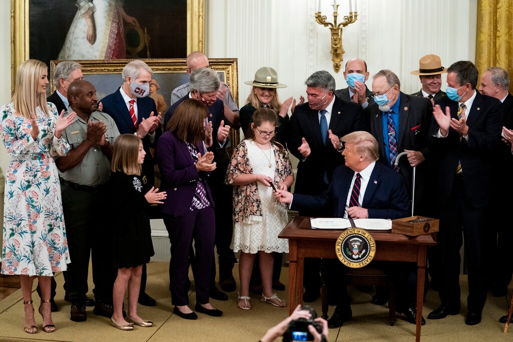 (Doug Mills | The New York Times) President Donald Trump hands out a pen he used to sign the Great American Outdoors Act, in the East Room of the White House in Washington, on Tuesday, Aug. 4, 2020. The bipartisan bill guarantees funding for federal land use efforts. The president claimed credit for Republicans.