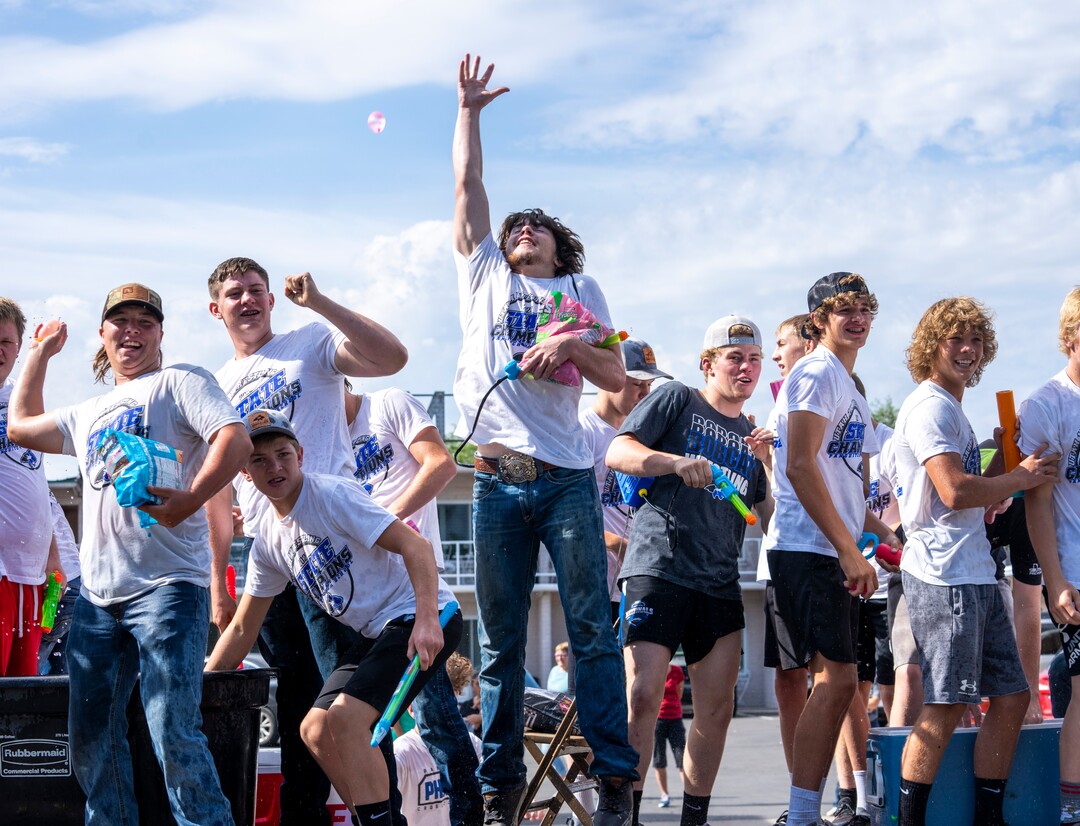(Rick Egan | The Salt Lake Tribune) The Panguitch High School wrestling team  tries to spray the parade crowd with water as they dodge water balloons in the Panguitch Pioneer Day Parade, on Saturday, July 23, 2022.
