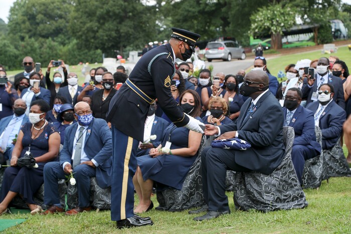 The Honor Guard presents the flag that was on his casket to his son, John-Miles Lewis, at the burial service for Rep. John Lewis at South-View Cemetery in Atlanta Thursday, July 30, 2020. (Alyssa Pointer/Atlanta Journal-Constitution via AP, Pool)