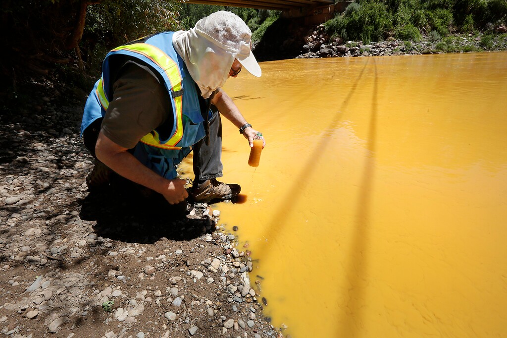 FILE - In this Aug. 6, 2015 file photo, Dan Bender, with the La Plata County Sheriff's Office, takes a water sample from the Animas River near Durango, Colo. after the accidental release of an estimated 3 million gallons of waste from the Gold King Mine by a crew led by the U.S. Environmental Protection Agency. The EPA said Friday, Jan. 13, 2017 that it won’t pay claims totaling more than $1.2 billion for economic damages from the spill, saying the law prohibits it. (Jerry McBride /The Durango Herald via AP, File)