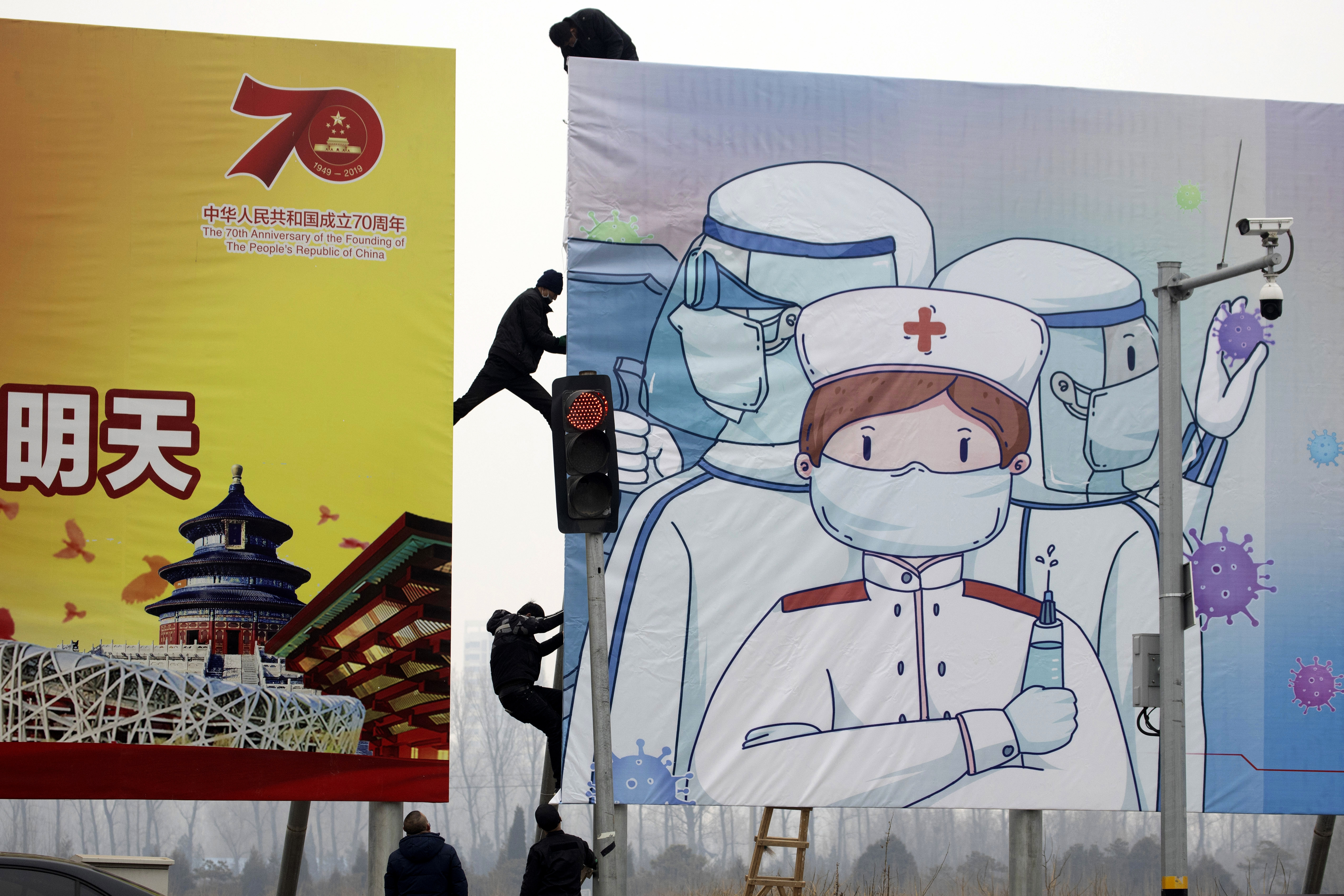 (Ng Han Guan | AP) Workers put up government propaganda to fight against the viral outbreak in Beijing, China on Thursday, Feb. 20, 2020. A viral outbreak that began in China has infected more than 75,000 people globally. The World Health Organization has named the illness COVID-19, referring to its origin late last year and the coronavirus that causes it.