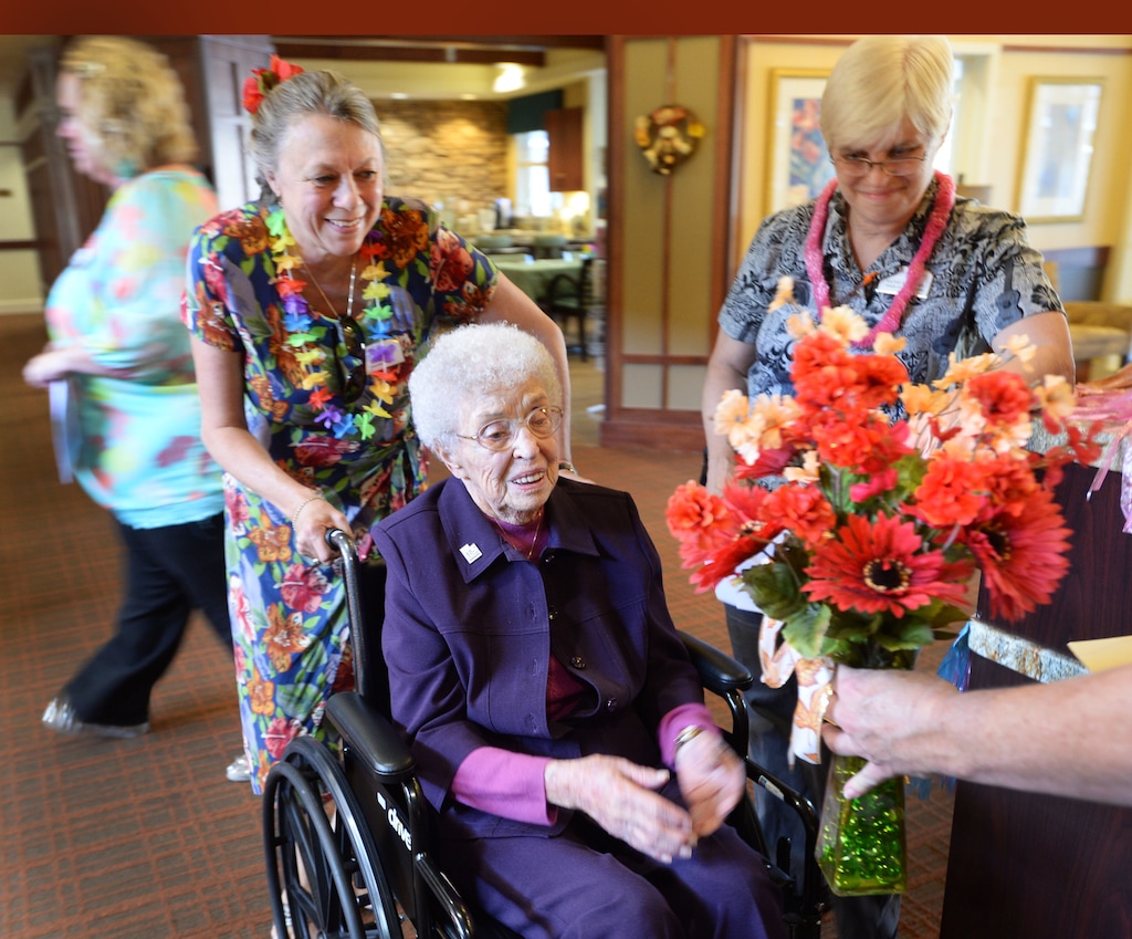 (Steve Griffin | Tribune file photo) Lou Calder, a long-time resident at The Wellington Senior Living, receives a bouquet of flowers during her 105th birthday celebration at the senior living center in Salt Lake City Wednesday, September 17, 2014. Calder was celebrating her birthday during a Luau party at the center.