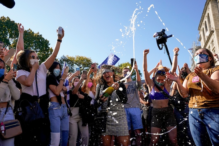 Amanda Madden sprays champagne as people celebrate at Black Lives Matter Plaza after CNN called the race in favor of Democratic presidential candidate Joe Biden over Pres. Donald Trump to become the 46th president of the United States, Saturday, Nov. 7, 2020, in Washington. His victory came after more than three days of uncertainty as election officials sorted through a surge of mail-in votes that delayed the processing of some ballots. (AP Photo/Alex Brandon)