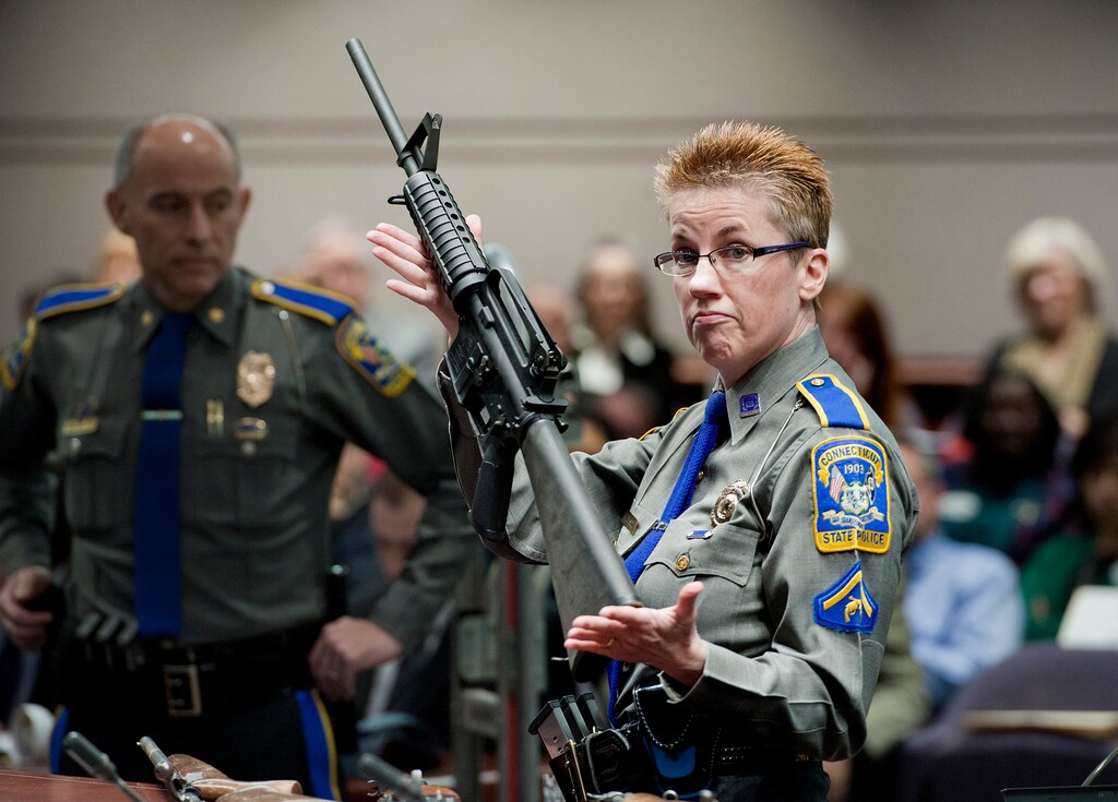 (Jessica Hill | Associated Press file photo) In this Jan. 28, 2013, file photo, firearms training unit Detective Barbara J. Mattson, of the Connecticut State Police, holds up a Bushmaster AR-15 rifle, the same make and model of gun used by Adam Lanza in the Sandy Hook School shooting, during a hearing of a legislative subcommittee in Hartford, Conn. Connecticut is one of five states that have passed "red flag laws" that allow the seizure of guns before people can commit acts of violence.