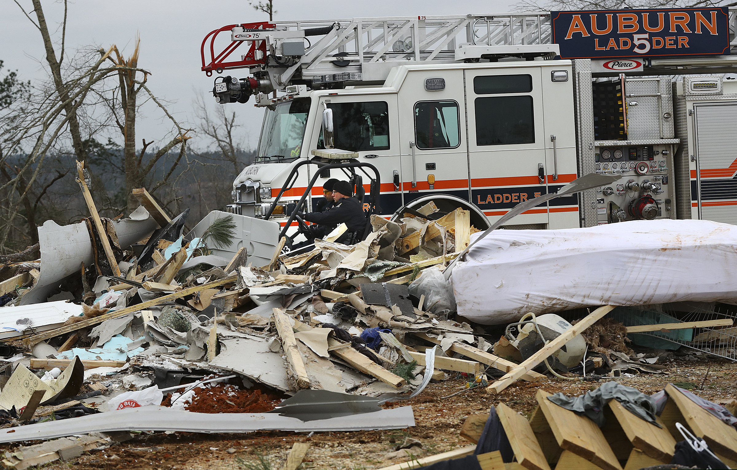 Rescue workers in a four wheeler pass by the wreckage of a home along Lee Road 38 after a Sunday night tornado on Monday, March 4, 2019, in Beauregard, Ala.   (Curtis Compton/Atlanta Journal-Constitution via AP)