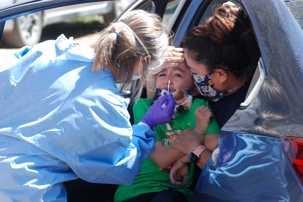 Ashley Pyne, right, helps her son, Elijah, complete a nasal swipe for COVID-19 testing in Picuris Pueblo, N.M., Thursday, April 24, 2020. Small Native American pueblo tribes across New Mexico are embracing extraordinary social distancing measures that include guarded roadblocks and universal testing for the coronavirus in efforts to insulate themselves from a contagion with frightening echoes of the past.  (AP Photo/Morgan Lee)