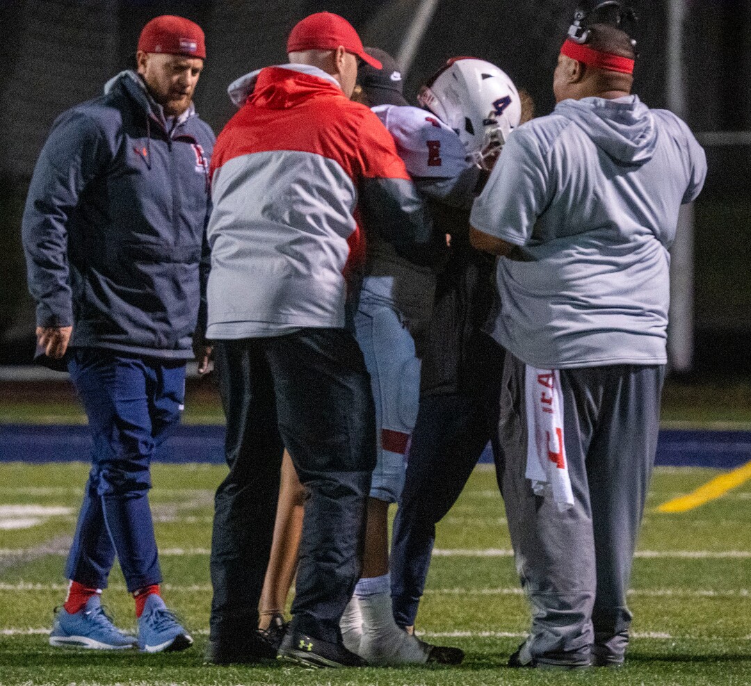 (Rick Egan | The Salt Lake Tribune) Coaches and medical personnel gather around East High Quarterback Siona Vailahi (4) is helped to his feet after he  was knocked down by a hard hit, in prep football action between Corner Canyon Chargers and the East Leopards, on Saturday, Aug. 21, 2021. He did not return to the game.