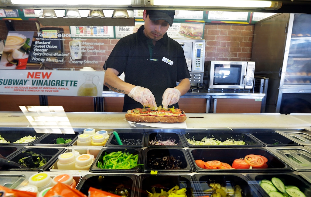 (Ted S. Warren | The Associated Press) In this March 3, 2015, file photo, Roberto Castelan makes a sandwich at a Subway sandwich franchise in Seattle. Subway is changing up its loyalty program, letting customers earn $2 discounts instead of free Footlong sandwiches. The change, taking place in March 2018, is part of Subway’s plan to lure people back to the sandwich chain.