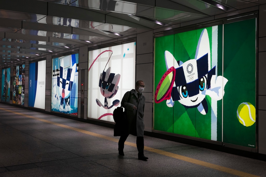 (Jae C. Hong | AP) A man with a mask walks past large displays promoting the Tokyo 2020 Olympics Monday, Feb. 24, 2020, in Tokyo.