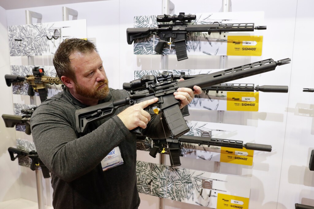 Bryan Oberc, Munster, Ind., tries out an AR-15 from Sig Sauer in the exhibition hall at the National Rifle Association Annual Meeting in Indianapolis, Saturday, April 27, 2019. (AP Photo/Michael Conroy)