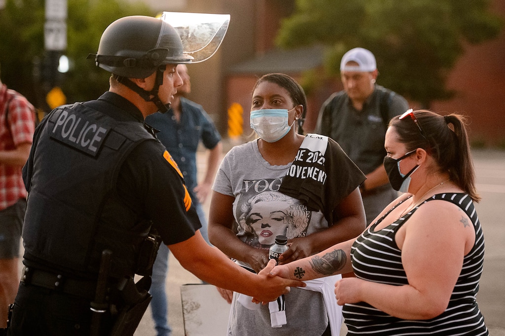 (Trent Nelson  |  Tribune file photo) A Salt Lake City police officer shakes hands with protesters marching for Black Lives Matter in this June 2, 2020, file photo. A racial equity commission is recommending changes in policing and wants feedback from residents. A virtual public hearing is scheduled for Jan. 20.