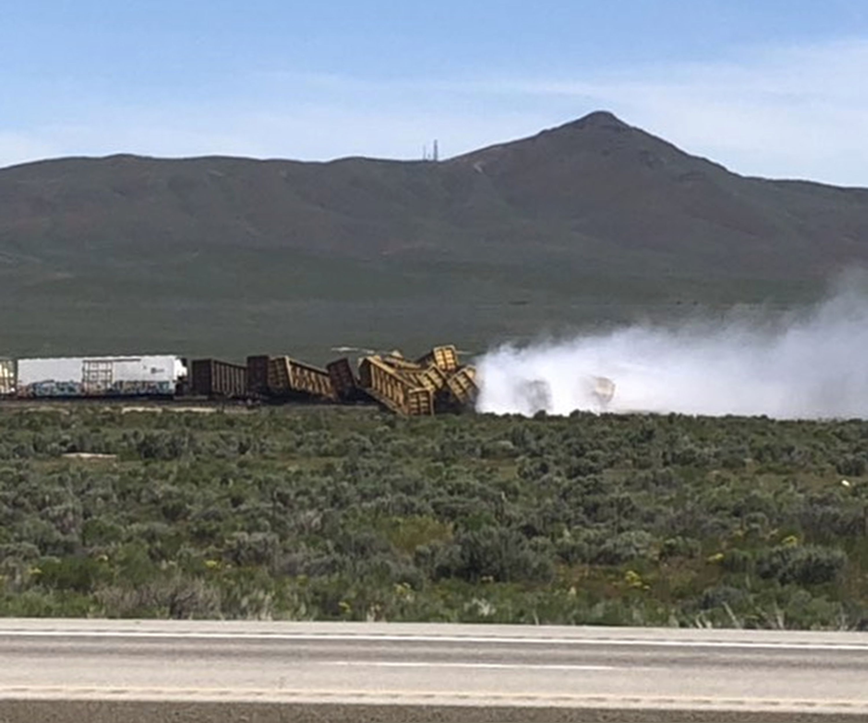 (Michael Lyday via AP) In this photo provided by Michael Lyday shows a train derailment and potential hazardous materials spill east of Wells, Nev., Wednesday, June 19, 2019. A 60-mile stretch of U.S. Interstate 80 in northeast Nevada was closed while emergency crews respond to the train derailment and potential hazardous materials spill east of Wells.