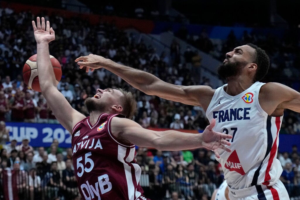 (Achmad Ibrahim | AP) France center Rudy Gobert (27) blocks a shot from Latvia guard Arturs Zagars (55) during the Basketball World Cup group H match between France and Latvia at the Indonesia Arena stadium in Jakarta, Indonesia, Sunday, Aug. 27, 2023.
