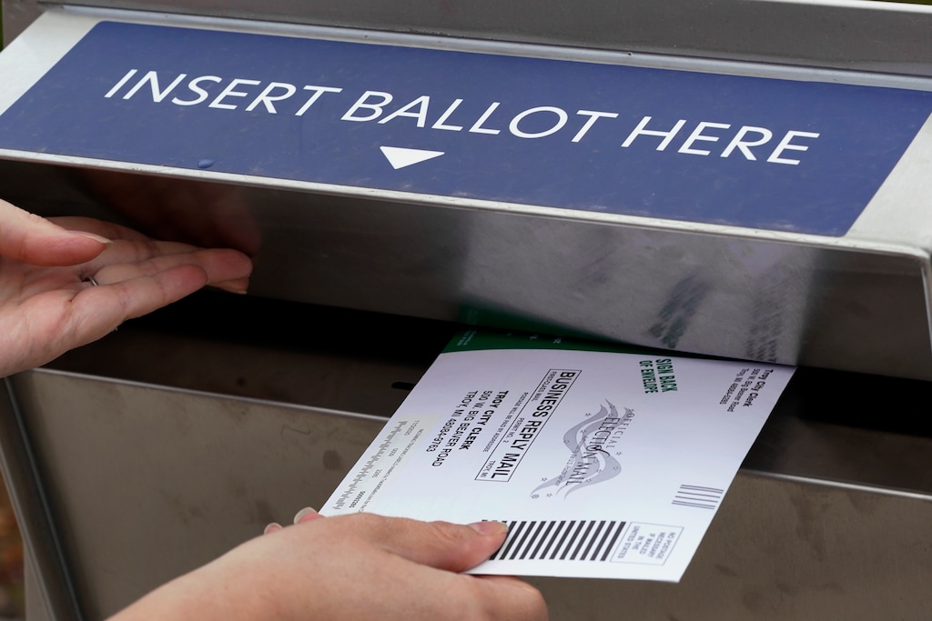 FILE - In this Thursday, Oct. 15, 2020, file photo, Nikki Schueller inserts her absentee voter ballot into a drop box in Troy, Mich. (AP Photo/Paul Sancya, File)