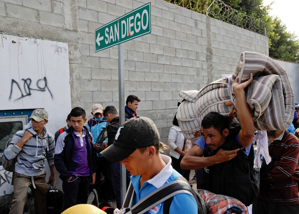 (Gregory Bull | AP Photo) Central American migrants wait in line for a meal at a shelter in Tijuana, Mexico, Wednesday, Nov. 14, 2018. Migrants in a caravan of Central Americans scrambled to reach the U.S. border, catching rides on buses and trucks for hundreds of miles in the last leg of their journey Wednesday as the first sizable groups began arriving in the border city of Tijuana.