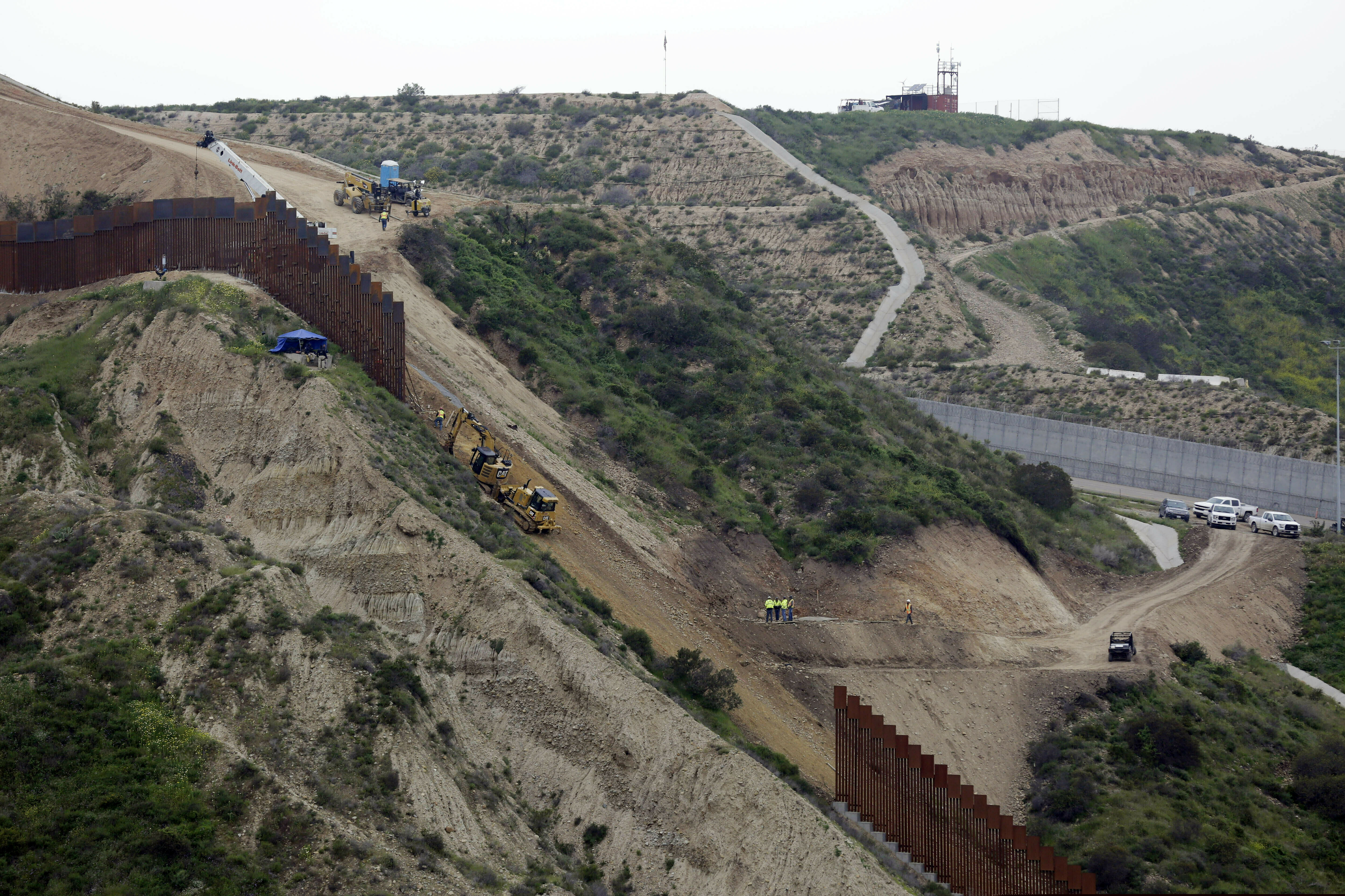 FILE - In this March 11, 2019 photo, construction crews replace a section of the primary wall separating San Diego, above right, and Tijuana, Mexico, below left, seen from Tijuana, Mexico. Acting Defense Secretary Patrick Shanahan has authorized the Army Corps of Engineers to begin planning and building 57 miles of 18-foot-high fencing in Yuma, Ariz., and El Paso, Texas, along the U.S. border with Mexico. (AP Photo/Gregory Bull)