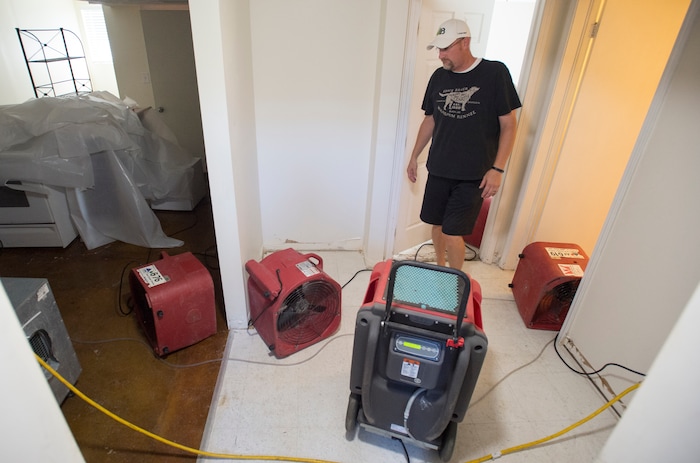 (Rick Egan  |  The Salt Lake Tribune)  Daren Gisseman walks among the fans as they dry the basement of  his home, after the carpet and everything was removed from his home on 2100 South. Tuesday, August 1, 2017.