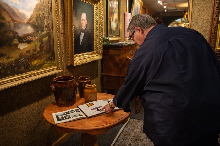 (Rachel Molenda  |  The Salt Lake Tribune)  Anthony B. Christensen, founder of Anthony's Fine Art & Antiques in Salt Lake City, explains the details of a pioneer era table made by William Bell on Thursday, July 19, 2018. The shop has a collection of early pioneer art and furniture on display.