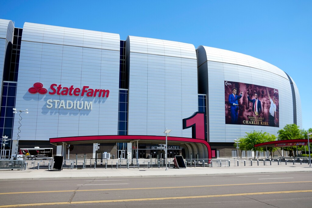 A large banner is installed prior to the Charlie Kirk memorial services at State Farm Stadium Saturday, Sept. 20, 2025, in Glendale, Ariz. A man was arrested on Friday after entering the venue with a gun and falsely claiming to be a law enforcement officer, officials said. (AP Photo/Ross D. Franklin)