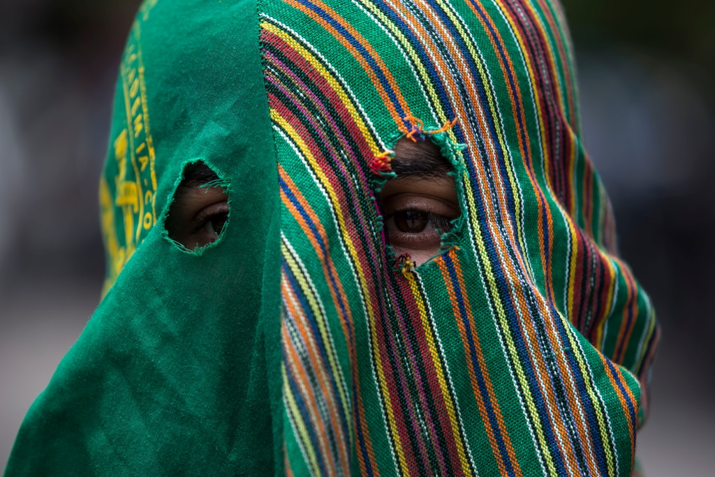 (Oliver de Ros | AP file photo) A hooded agronomy student protests outside a hotel in Guatemala City where lawmakers were July 31, 2019, to vote on a deal that Guatemalan President Jimmy Morales' government signed with Washington that would force Salvadoran and Honduran migrants to request asylum in Guatemala instead of the United States.