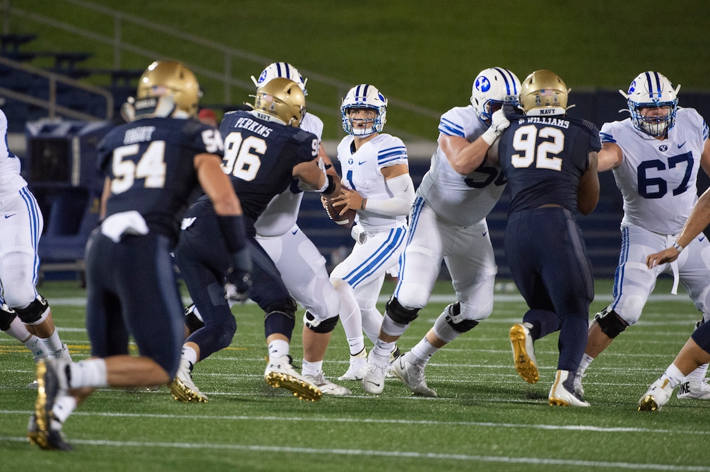 (Tommy Gilligan | AP) BYU quarterback Zach Wilson, center, looks to throw downfield as Navy defensive tackles Jackson Perkins (96) and Deondrae Williams (92) apply pressure during the first half of an NCAA college football game, Monday, Sept. 7, 2020, in Annapolis, Md.